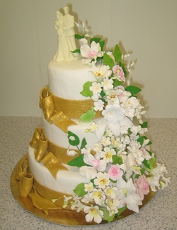 Cвадебный трехъярусный торт 
с золотыми лентами, букетом и фигуркой